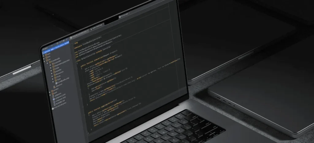 Ordinateur portable vu de biais, du code PHP ouvert dans un éditeur au thème sombre, à côté d’une tablette