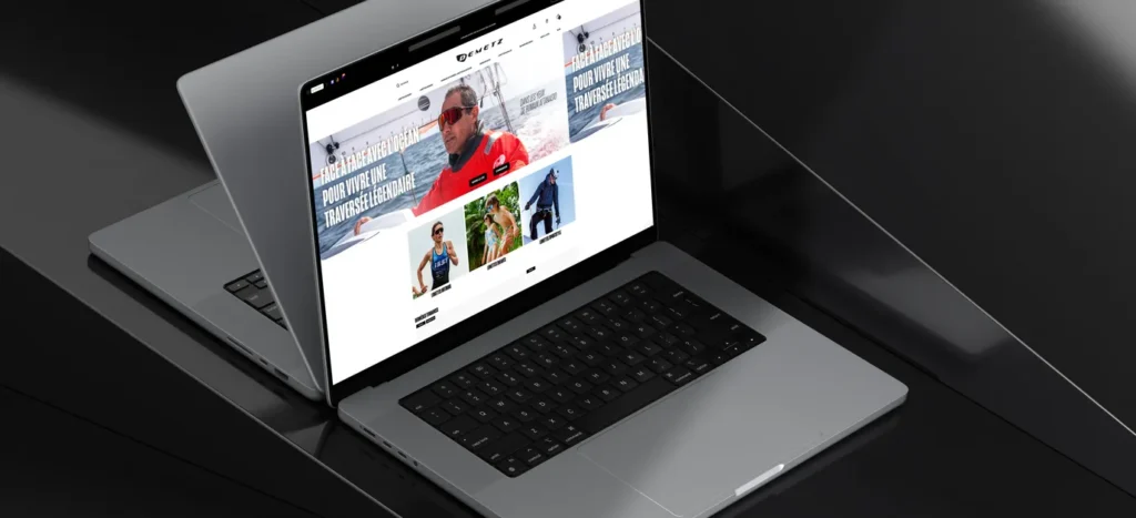 Ordinateur portable affichant la page d’accueil de la boutique Demetz : un navigateur en veste rouge et lunettes de soleil, et trois visuels de sports nautiques