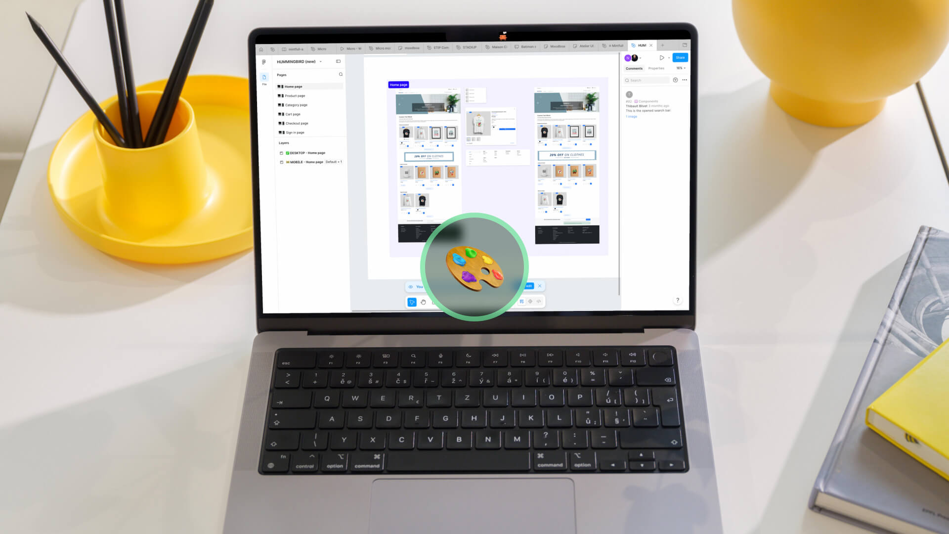 Laptop on a white desk showing a design mockup on screen, with a circular paint palette icon overlay; yellow pencil cup on left and yellow mug on the right.