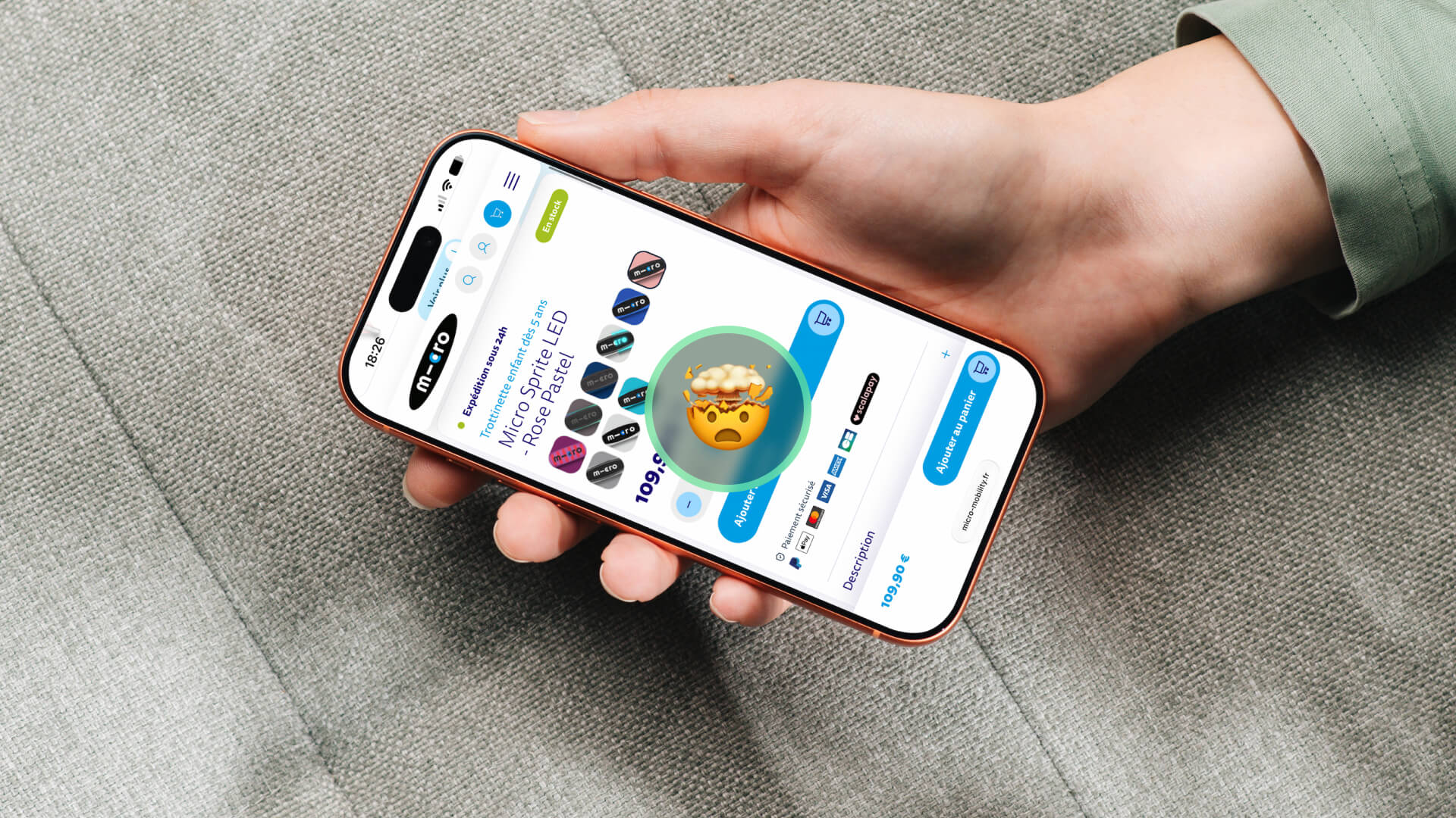 Hand holding a smartphone displaying a shopping app with a large emoji explosion icon in the center of the screen.
