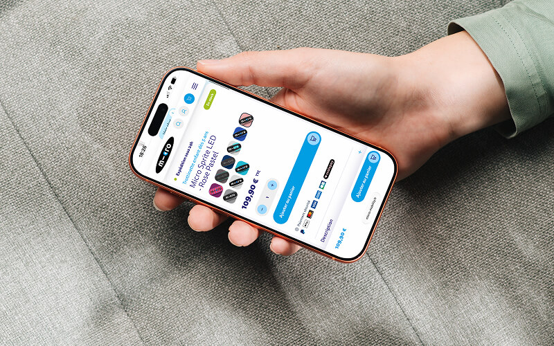 Hand holding a smartphone showing a product page with blue buttons and circular swatches on the screen.